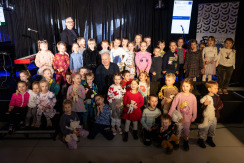 Grupa ludzi w sali kinowej muzeum. Dzieci uczestniczące w zajęciach z gwiazdą Piotrem Wojtasikiem
