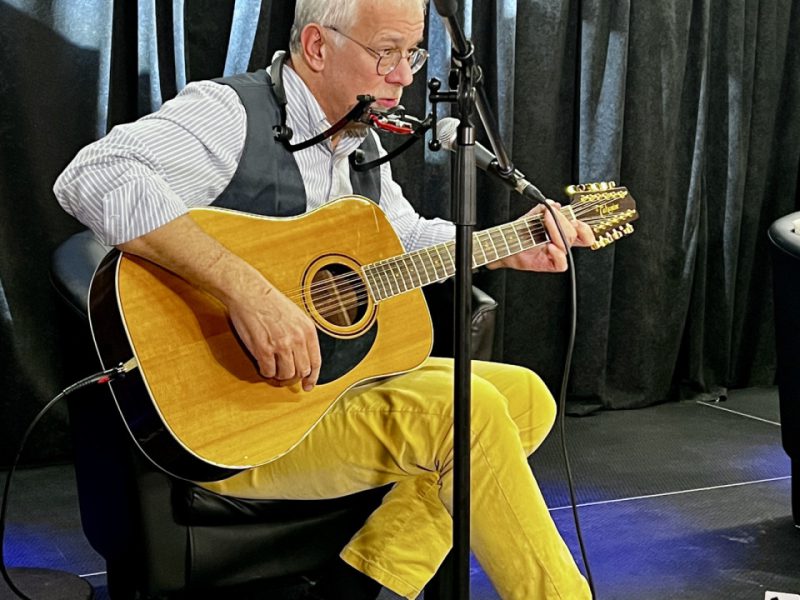 Sławomir Wierzcholski na scenie w muzeum, grający na gitarze