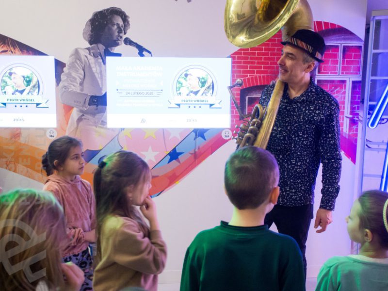 Piotr Wróbel grający na puzonie w czasie zajęć Małej Akademii Instrumentów i grupa dzieci