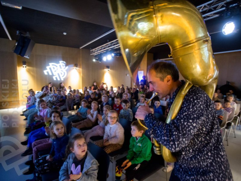 Piotr Wróbel grający na puzonie w czasie zajęć Małej Akademii Instrumentów i grupa dzieci