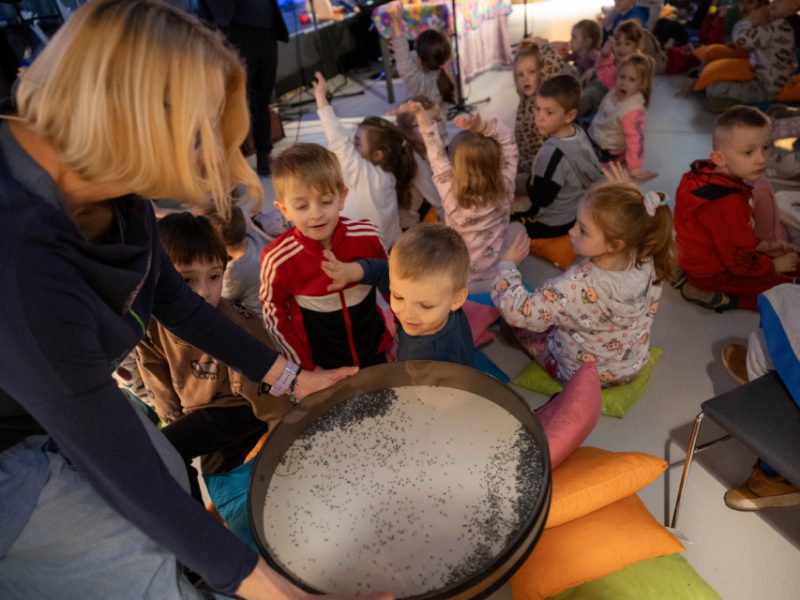 Grupa dzieci przy bębnach w sali muzeum, na zajęciach pt